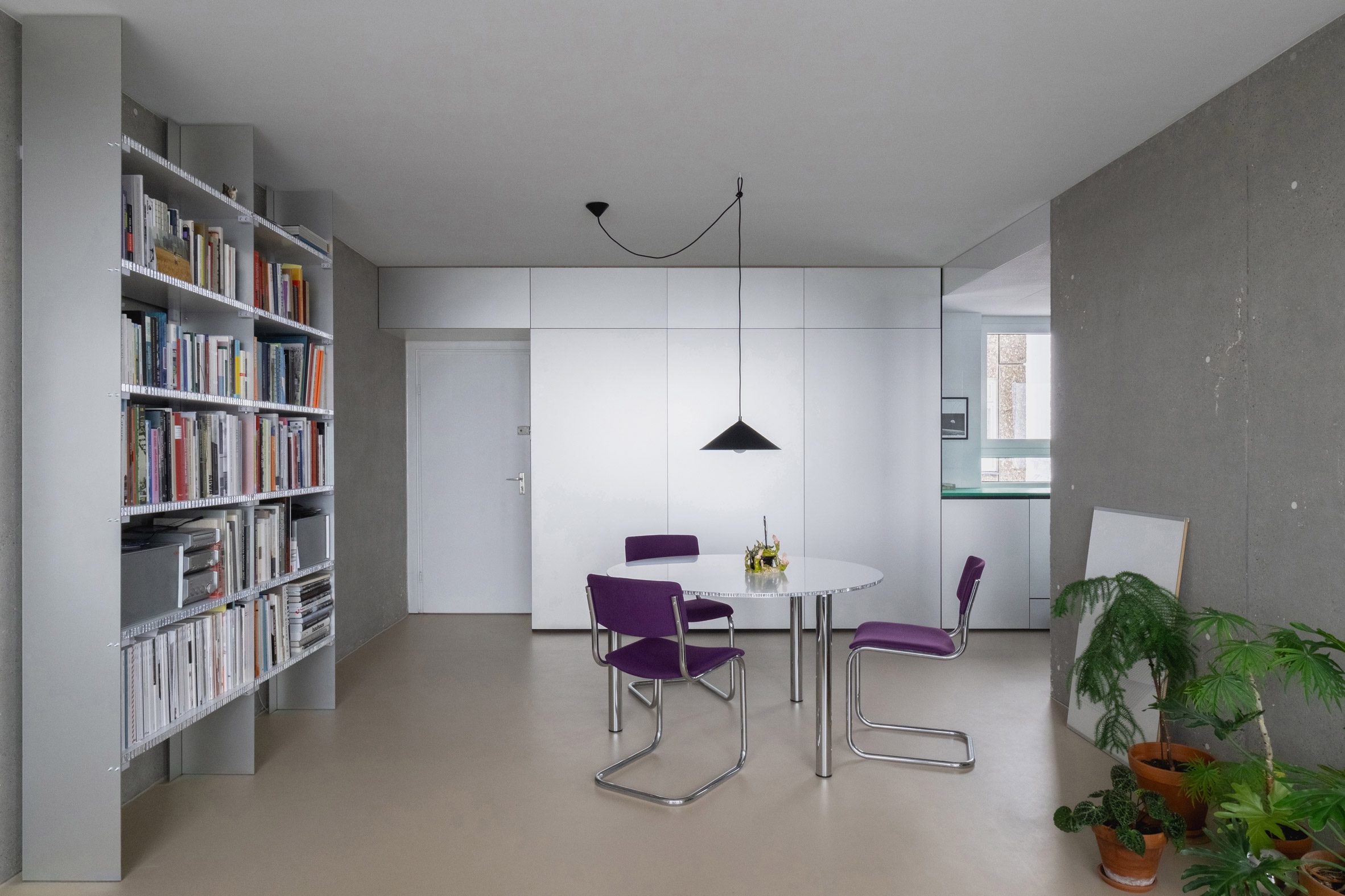 Dining space with bookcase and cantilever chairs around small circular table