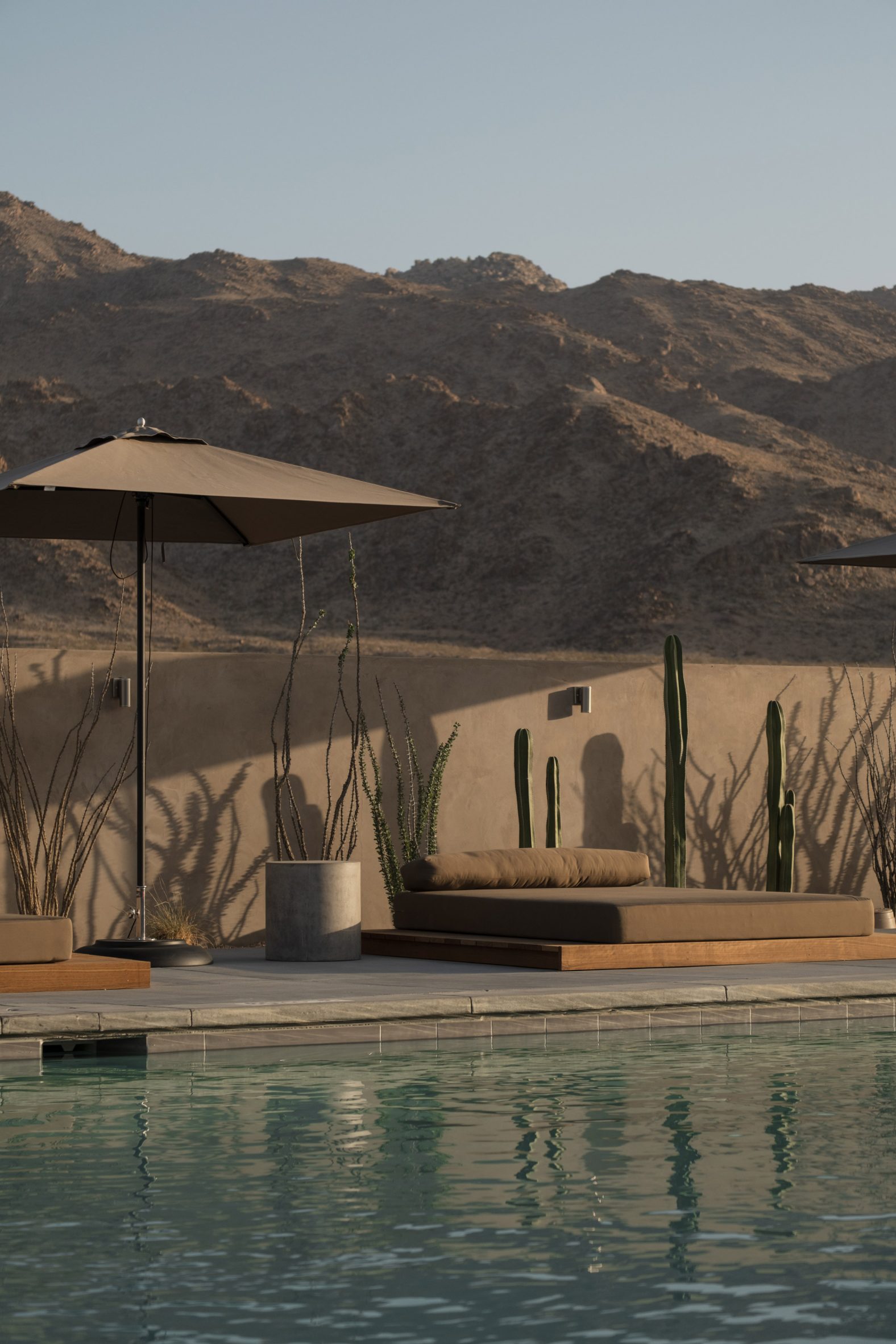 Swimming pool with low lounger, parasol, and mountains behind