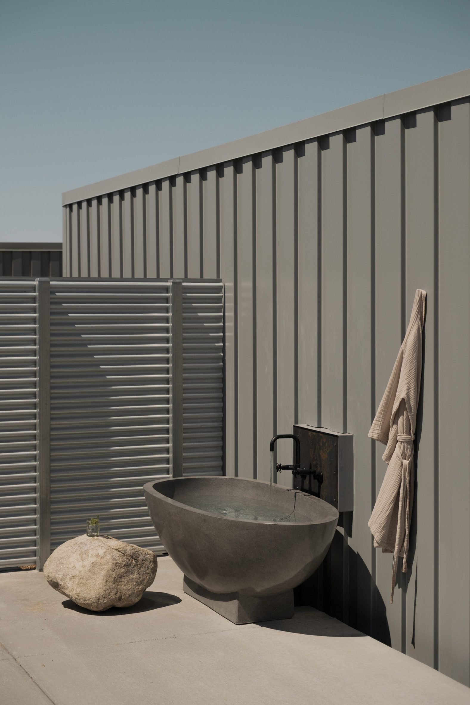 Outdoor bathtub beside a grey shipping container